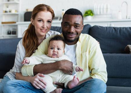 Interracial Couple Sitting on Couch with Baby in Home with Home Insurance in Temperance, MI